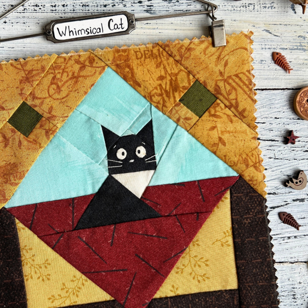 Whimsical Cat quilt block pattern featuring a black cat in a geometric patchwork design on a white wood background