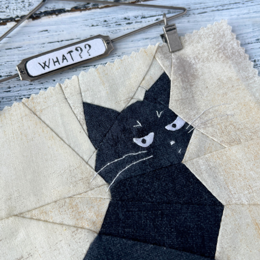 Close-up of What black cat quilt block showing expressive face and question sign