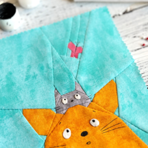 Close-up of Curious Cats quilt block showing ginger cat gray cat and butterfly detail
