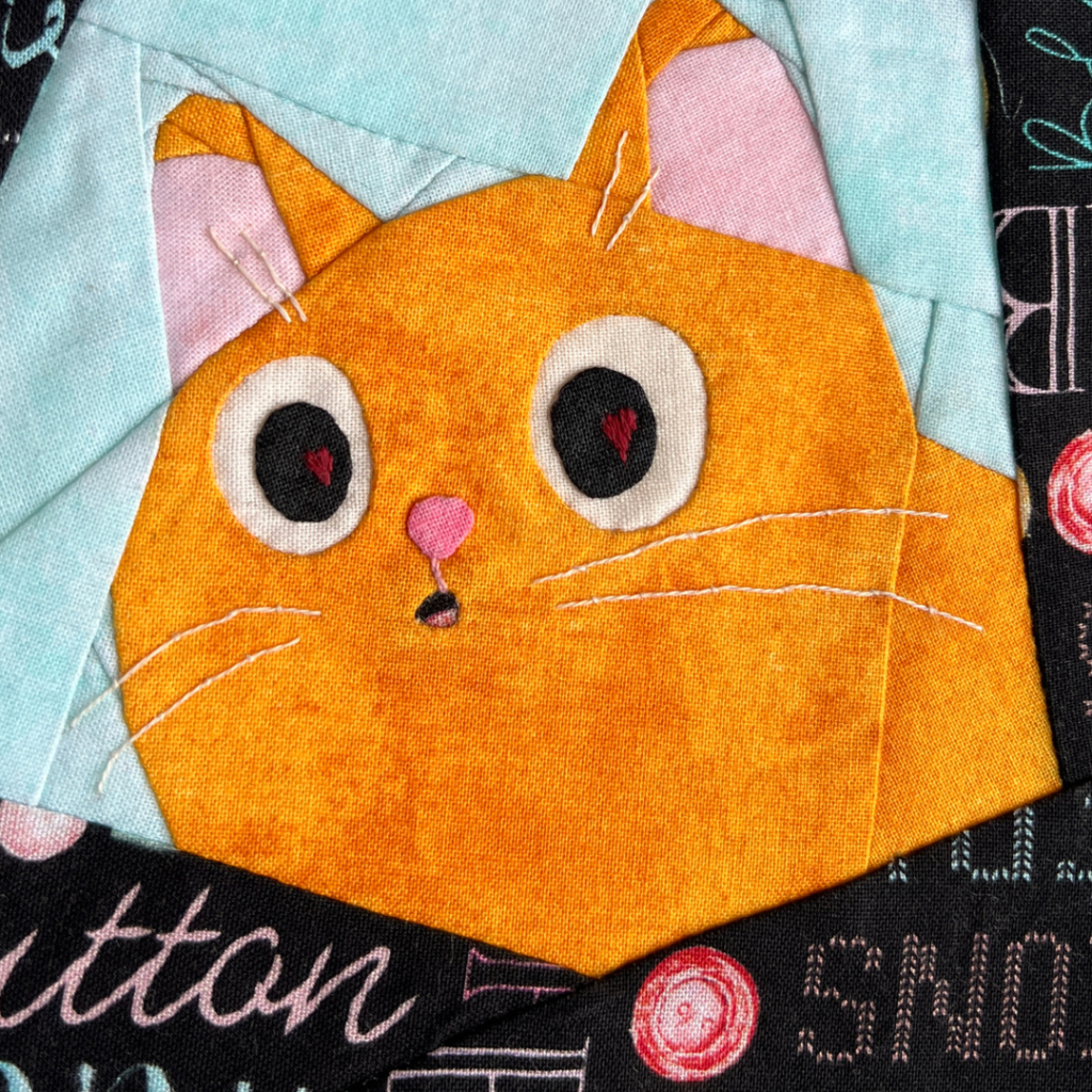Close-up of Love Is in the Eyes ginger cat quilt block showing face detail heart shaped eye accents and whiskers